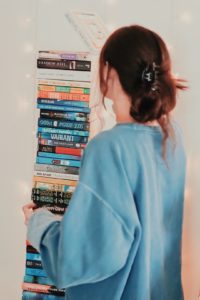 Grace with a precarious stack of books from all different publishers.