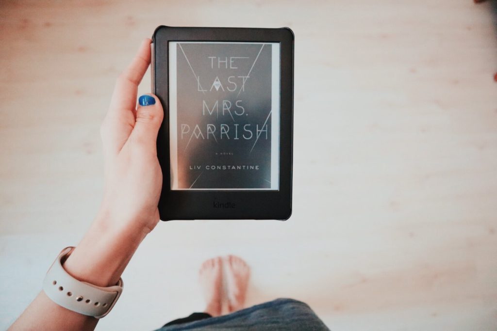 The Last Mrs. Parrish by Liv Constantine Kindle cover held in Grace's hand. Her feet and the floor are blurred behind.